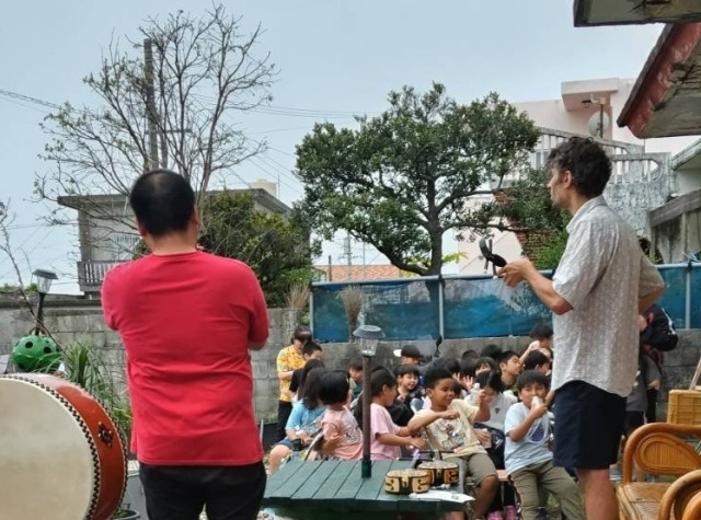 Photo from behind the stage, showing Ema playing and a part of the audience